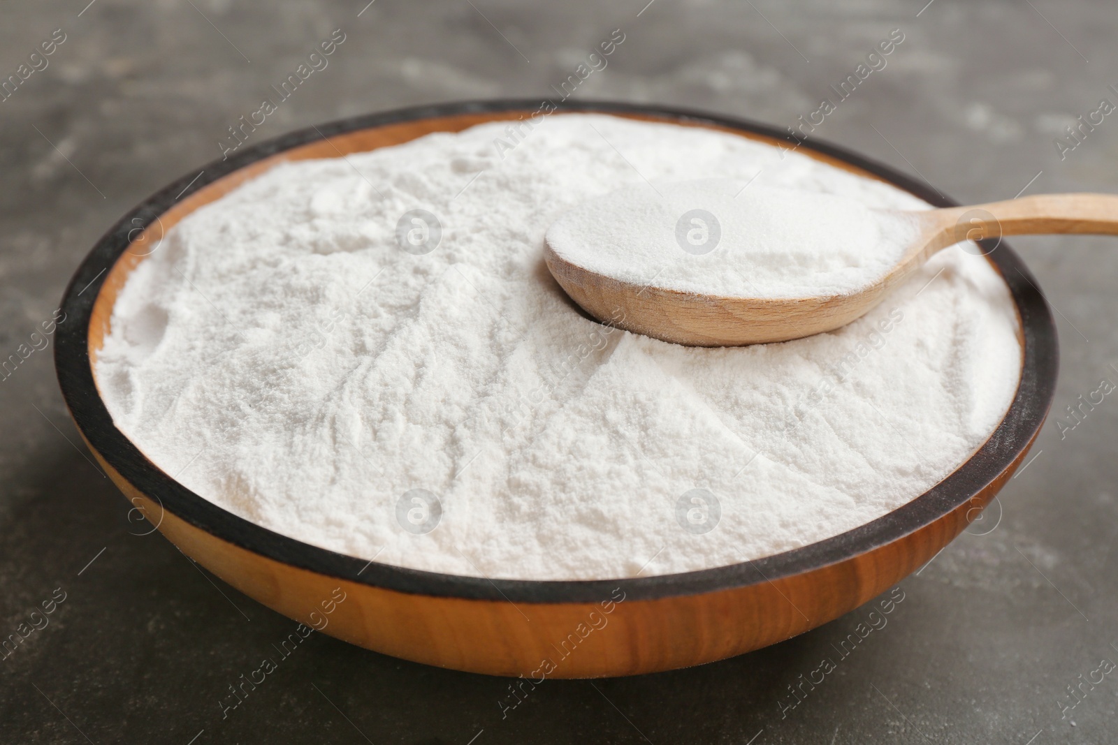 Photo of Bowl and spoon with baking soda on gray table