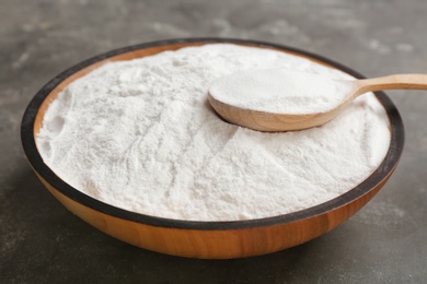 Photo of Bowl and spoon with baking soda on gray table