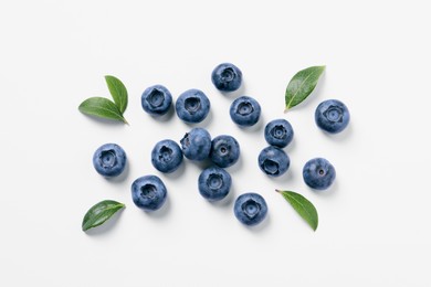 Photo of Tasty fresh blueberries with green leaves on white background, flat lay