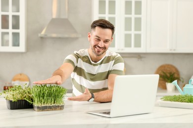 Photo of Teacher with microgreens conducting online course in kitchen. Time for hobby