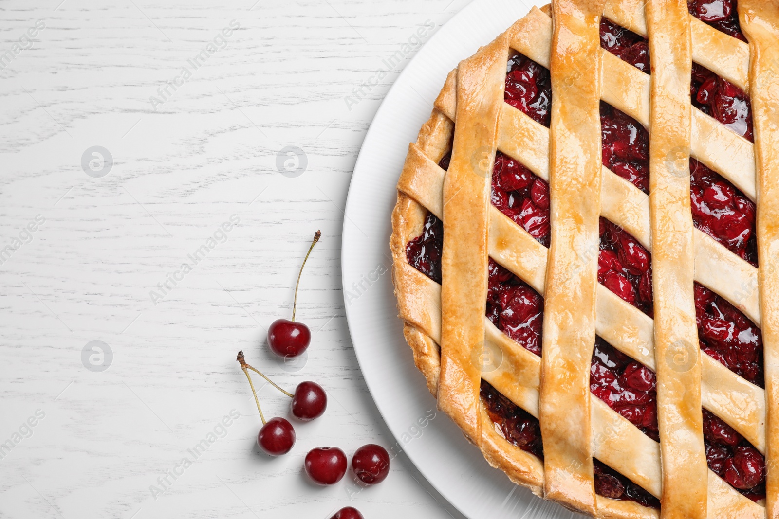 Photo of Delicious fresh pie and cherries on white wooden table, flat lay. Space for text