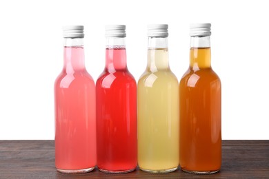 Photo of Delicious kombucha in glass bottles on wooden table against white background