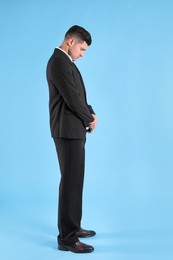 Photo of Upset man in suit on light blue background