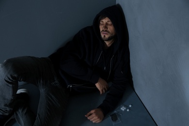 Photo of Passed out junkie after using drugs near grey wall