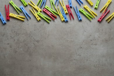 Photo of Colorful plastic clothespins on grey stone background, flat lay. Space for text