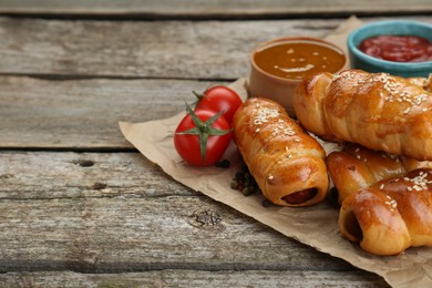 Photo of Delicious sausage rolls and ingredients on wooden table, closeup. Space for text
