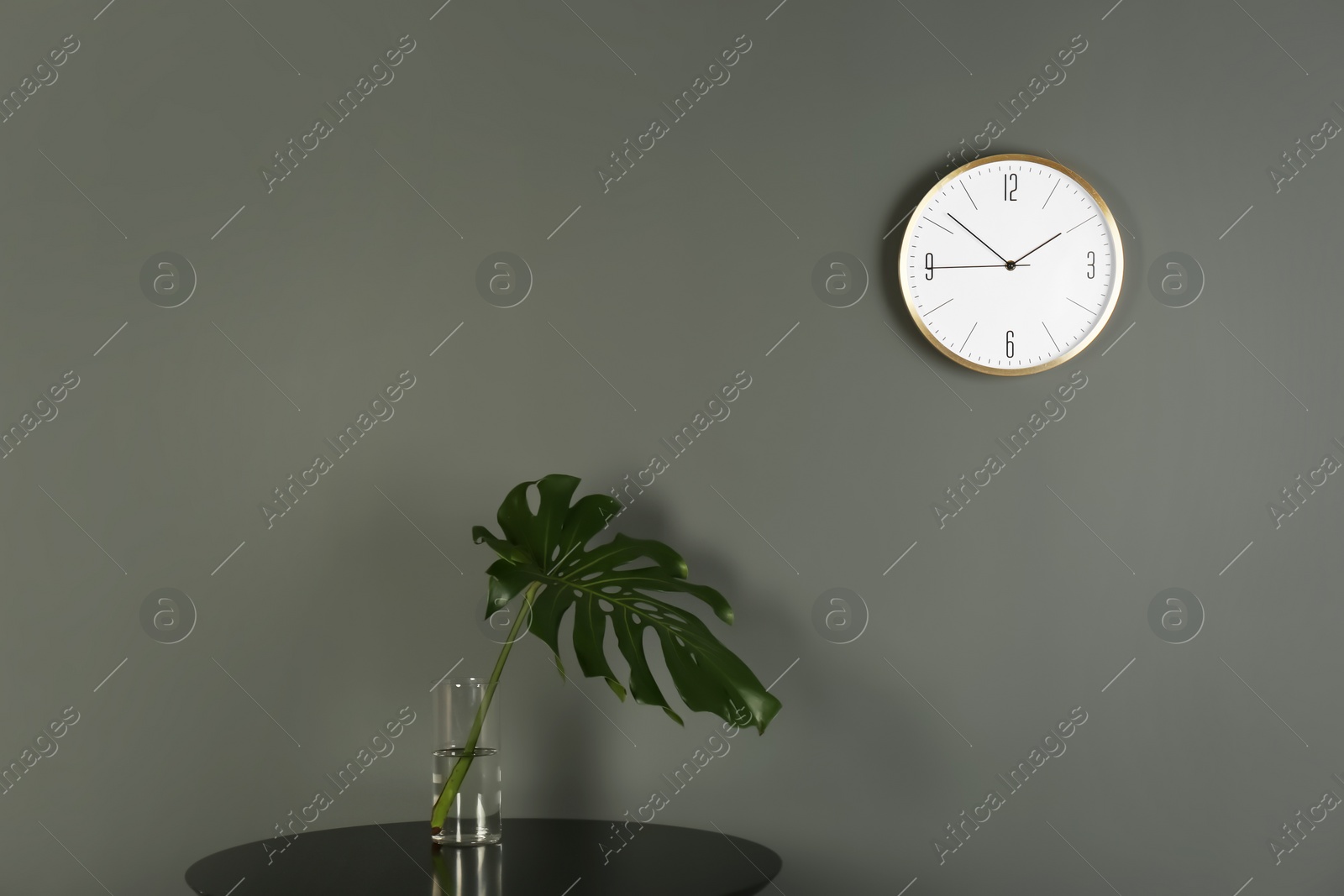 Photo of Analog clock on grey wall indoors. Time of day