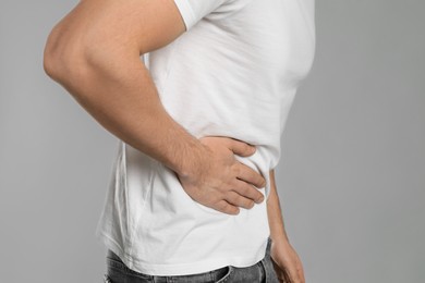 Photo of Man suffering from pain in lower right abdomen on light grey background, closeup. Acute appendicitis