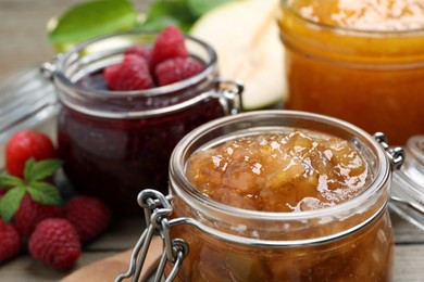 Photo of Jars with different jams and fresh berries on wooden table, closeup
