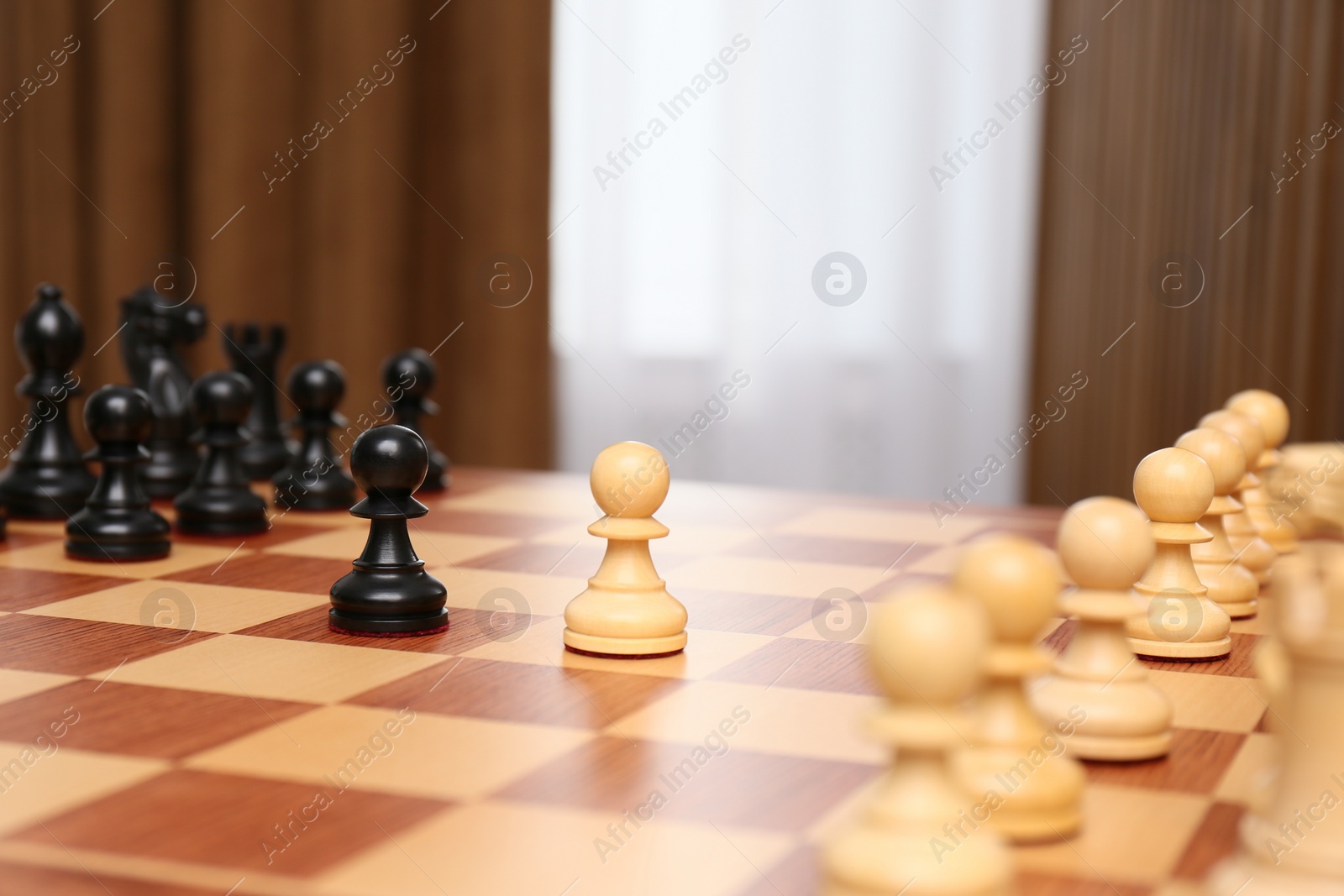 Photo of Black and white pieces among others on chessboard indoors