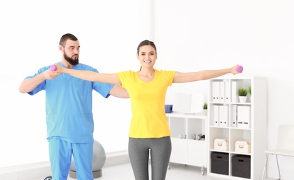 Photo of Physiotherapist working with young female patient in clinic