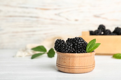 Photo of Bowl of fresh blackberry on table against wooden wall