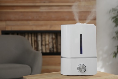 Modern air humidifier on wooden table indoors. Space for text