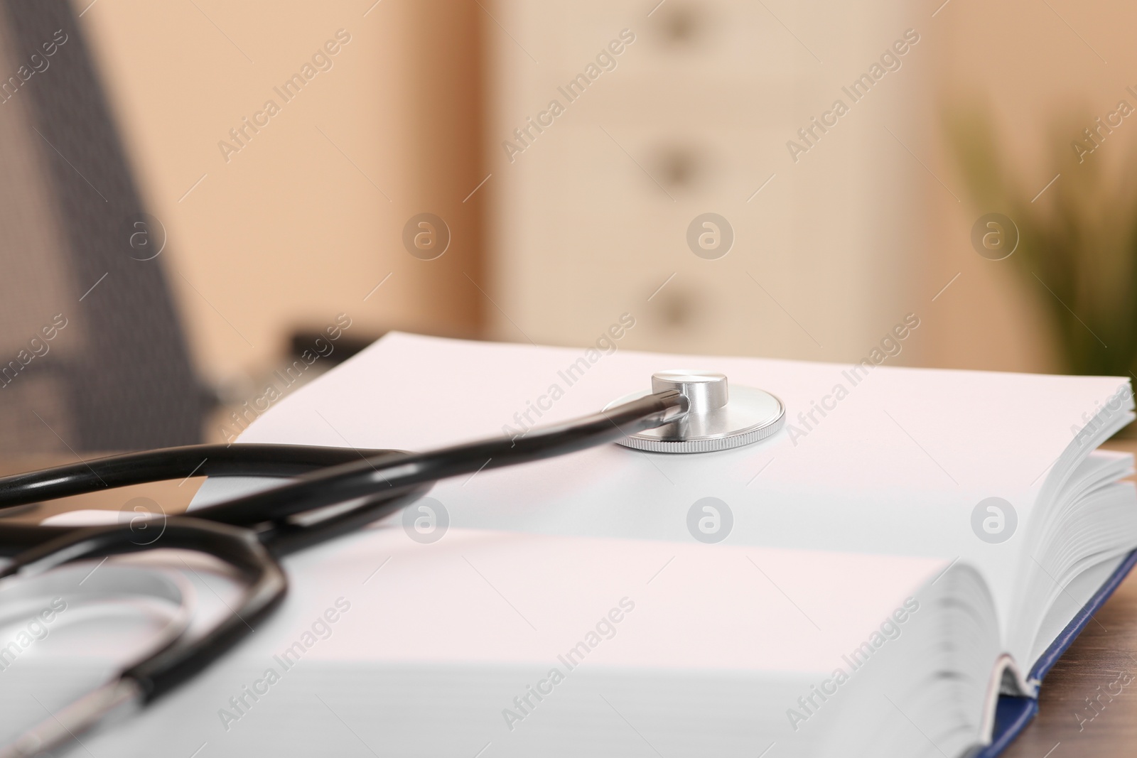 Photo of Book and stethoscope on wooden table indoors, space for text. Doctor education