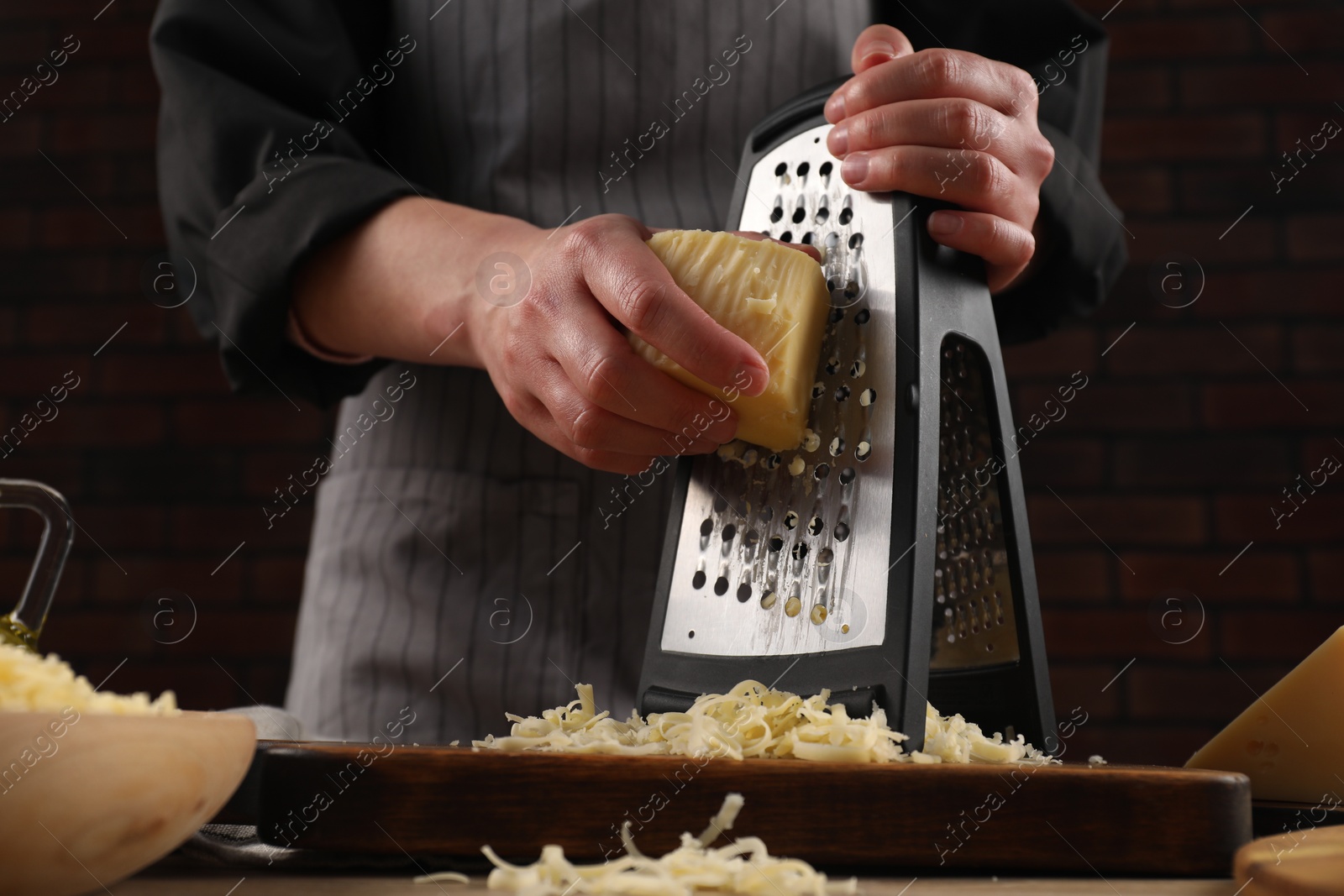 Photo of Woman grating cheese at wooden table, closeup