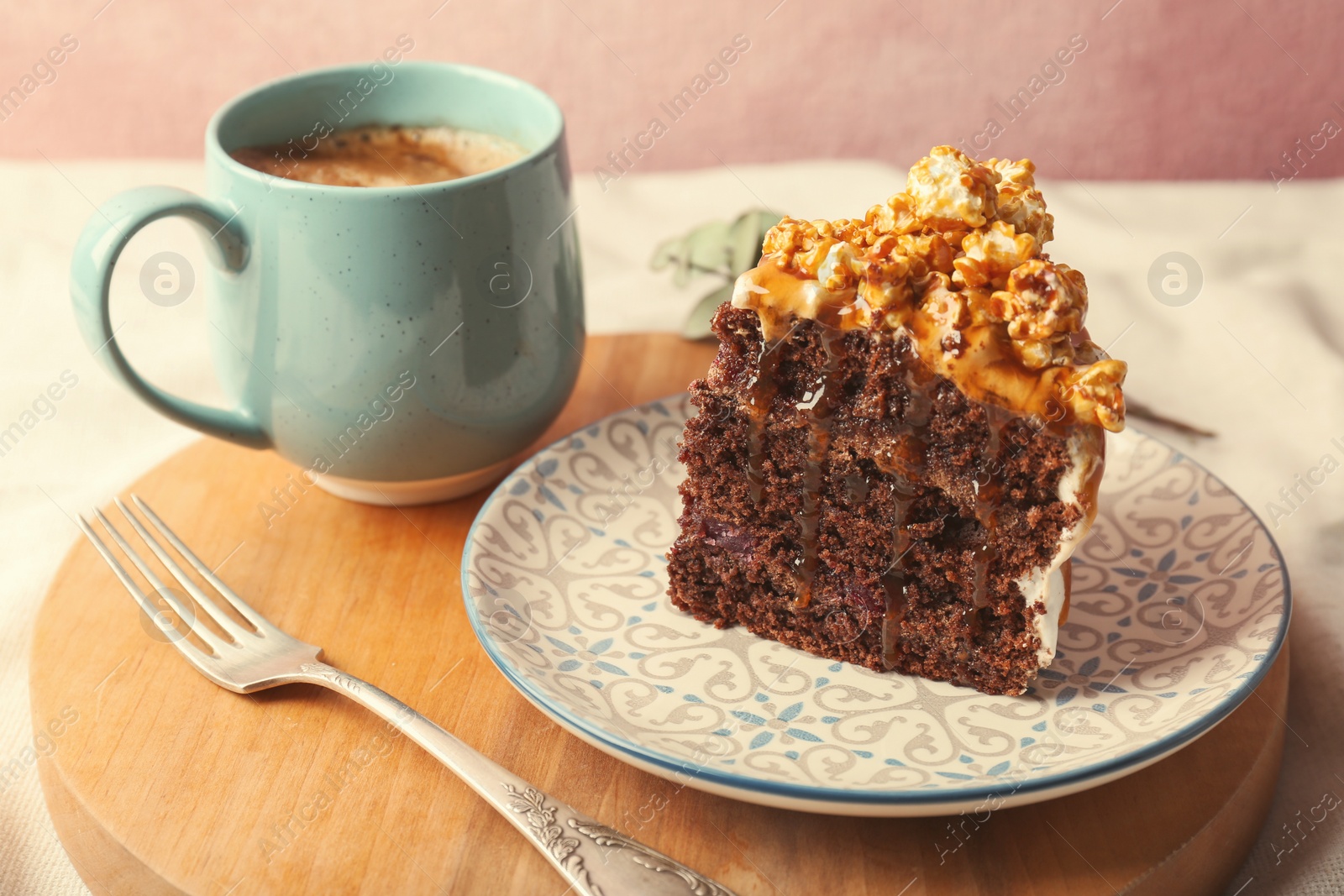 Photo of Piece of delicious homemade cake with caramel sauce and cup of coffee on wooden board