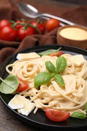 Photo of Delicious pasta with brie cheese, tomatoes and basil leaves on table, closeup