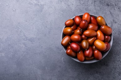 Ripe red dates in bowl on grey table, top view. Space for text
