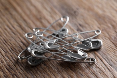 Pile of safety pins on wooden table, closeup