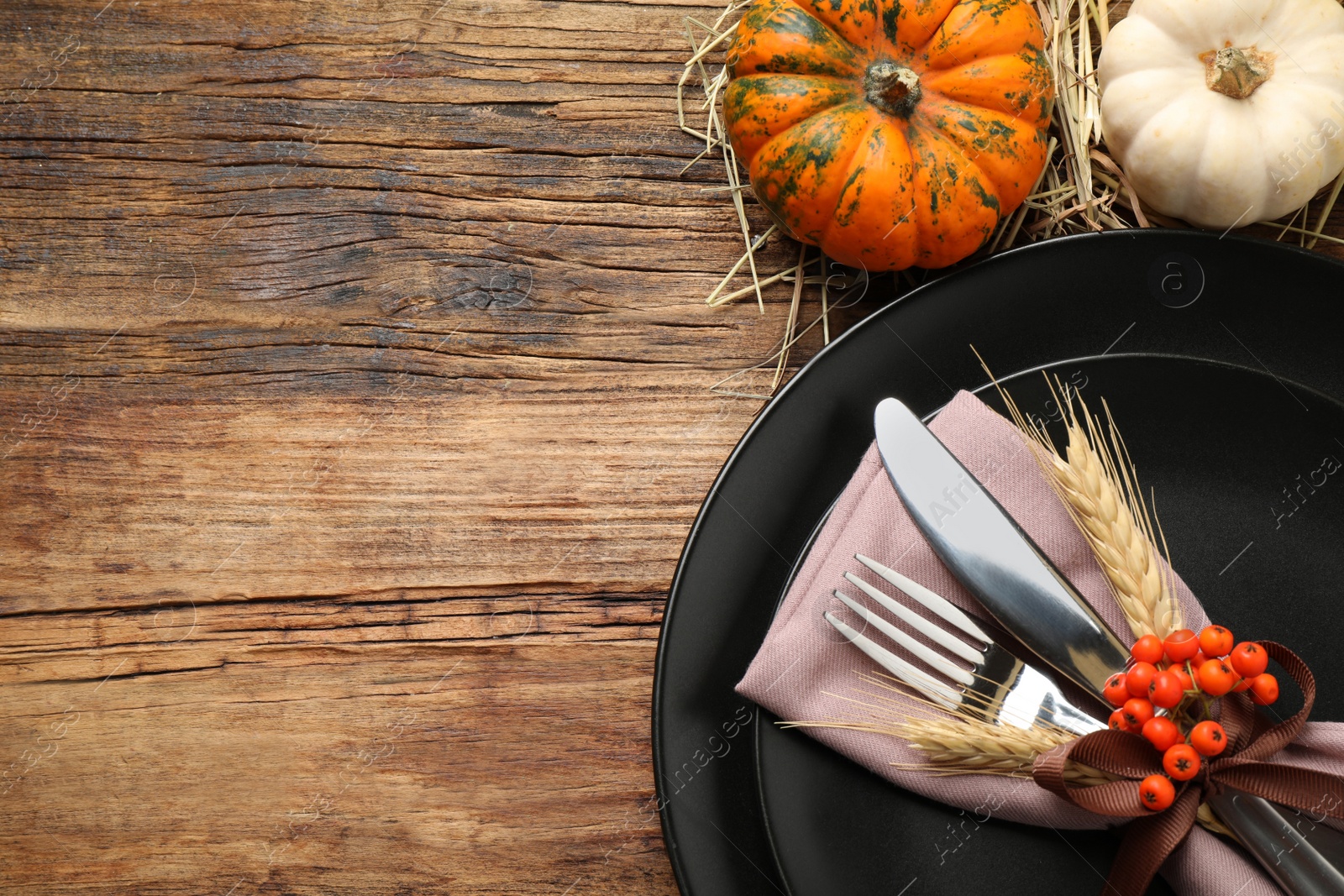 Photo of Festive table setting with pumpkins and space for text on wooden background, flat lay. Thanksgiving Day celebration