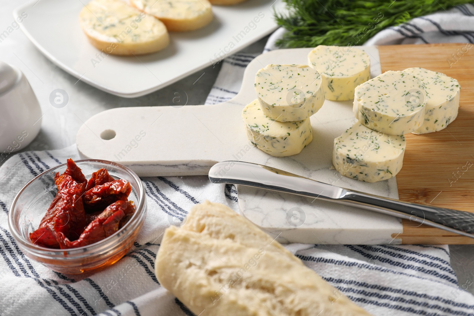 Photo of Tasty butter with dill, chili peppers, bread and knife on table