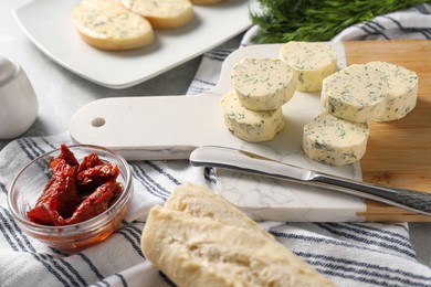 Photo of Tasty butter with dill, chili peppers, bread and knife on table