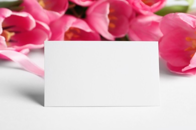 Photo of Beautiful spring tulips and blank card on white background, closeup with space for text. International Women's Day