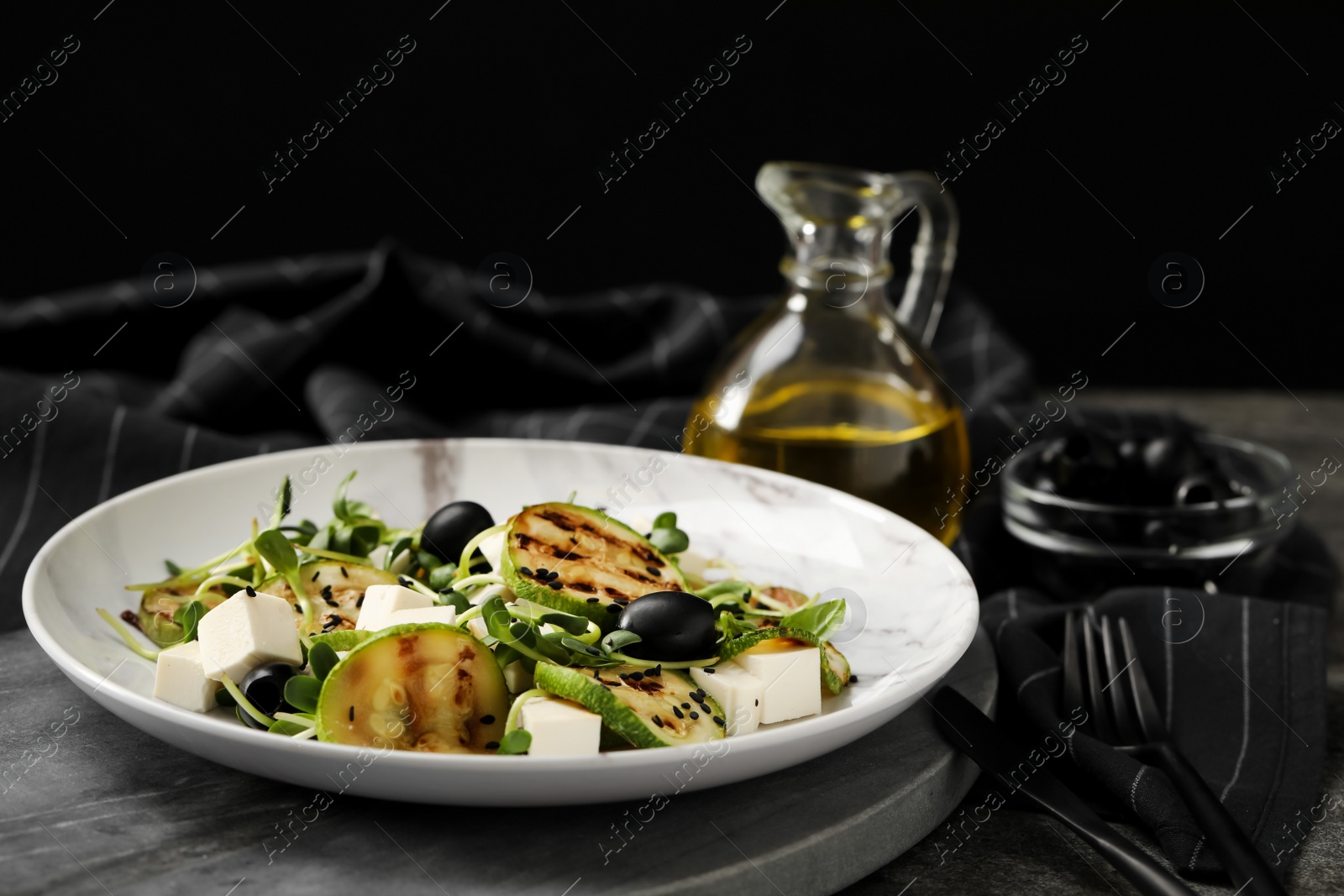 Photo of Delicious salad with grilled zucchini slices, feta cheese and olives on board, closeup