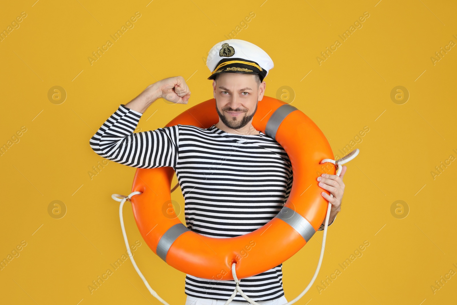 Photo of Sailor with orange ring buoy showing biceps on yellow background