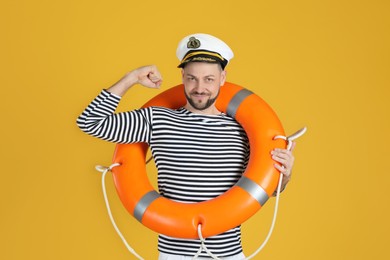 Photo of Sailor with orange ring buoy showing biceps on yellow background