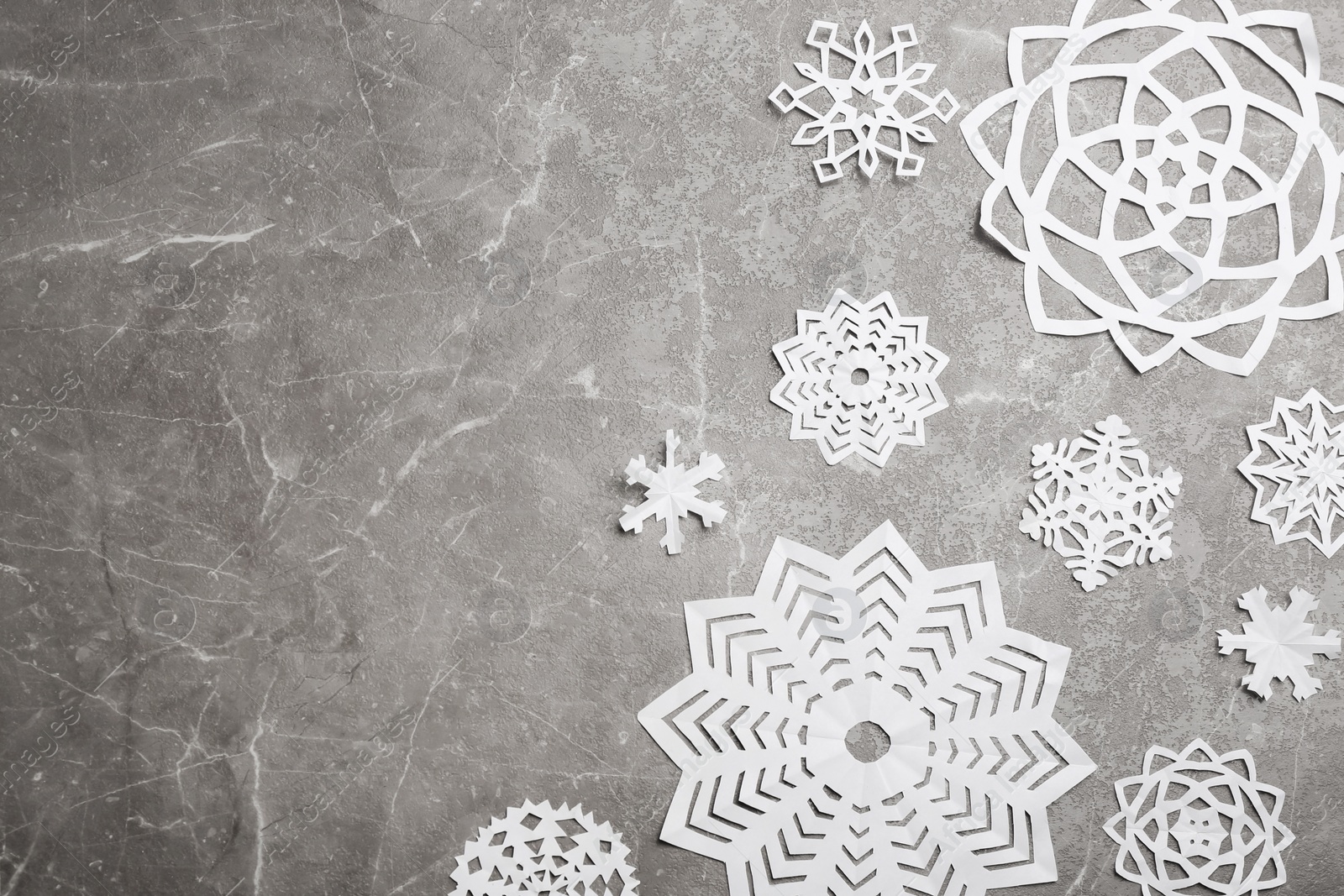 Photo of Many paper snowflakes on grey background, flat lay. Space for text