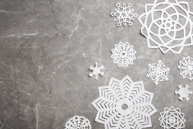 Many paper snowflakes on grey background, flat lay. Space for text