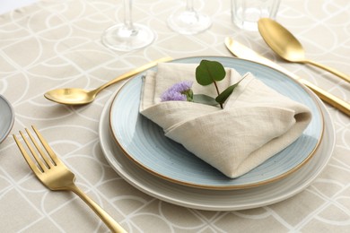 Stylish setting with cutlery, plates, napkin and floral decor on table