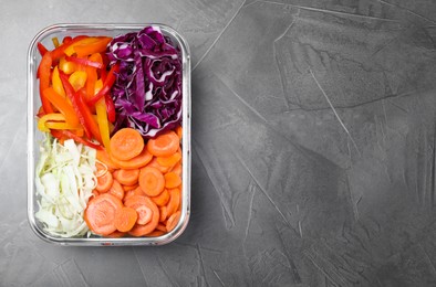 Fresh vegetables in glass container on grey table, top view. Space for text