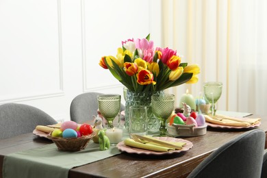 Photo of Easter celebration. Festive table setting with beautiful flowers and painted eggs