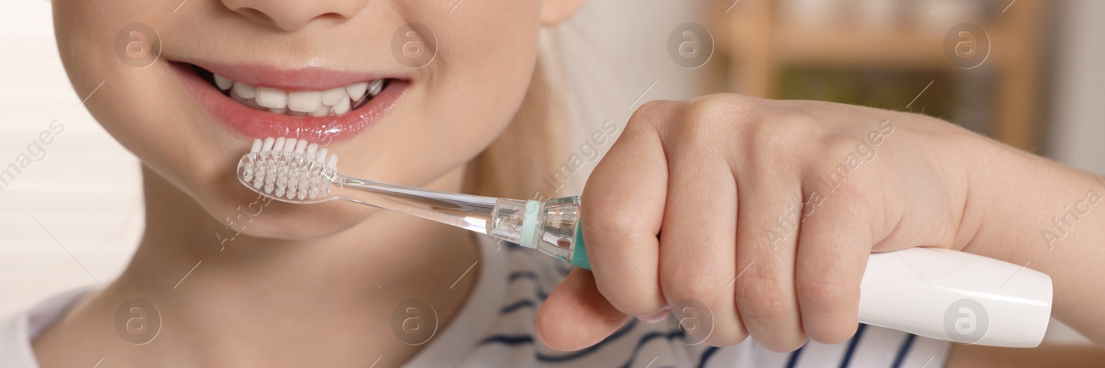 Image of Little girl brushing her teeth with electric toothbrush in bathroom, closeup. Banner design