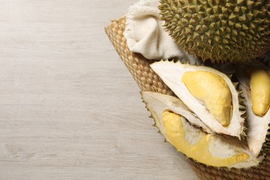 Photo of Fresh ripe durians on light wooden table, top view. Space for text
