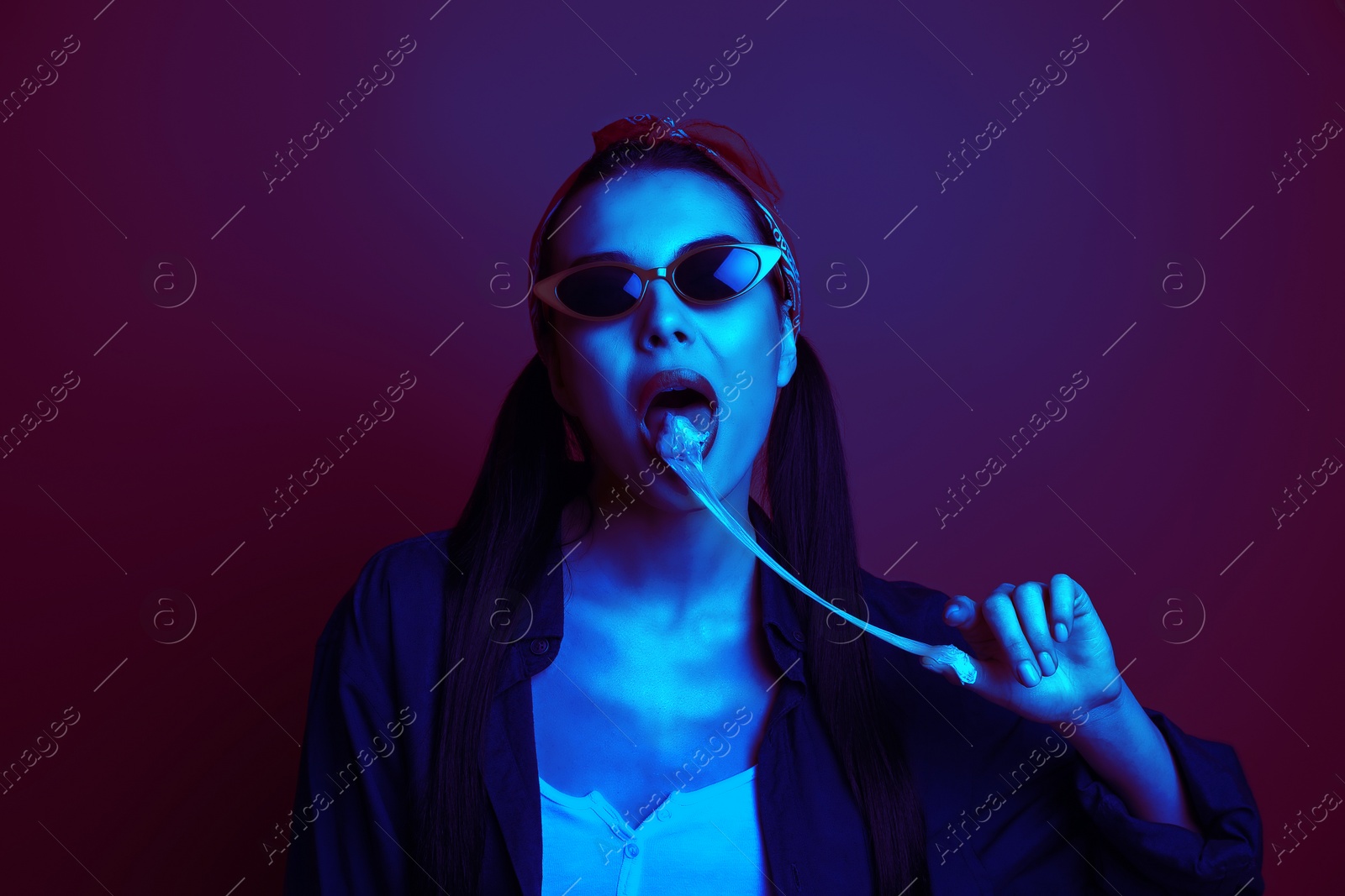 Image of Fashionable young woman with chewing bubblegum in neon lights