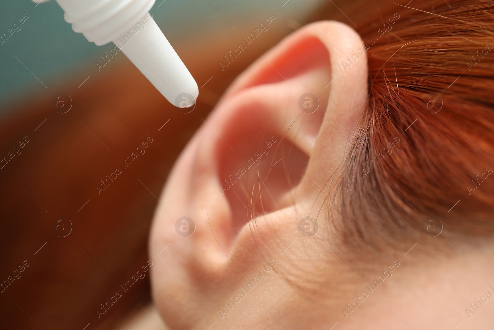 Photo of Woman applying medical ear drops, macro view