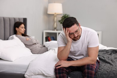 Offended couple ignoring each other after quarrel in bedroom, selective focus. Relationship problems