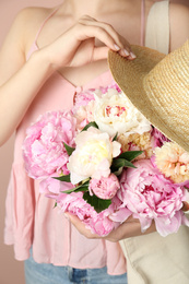Photo of Woman with bouquet of beautiful peonies in bag and hat, closeup