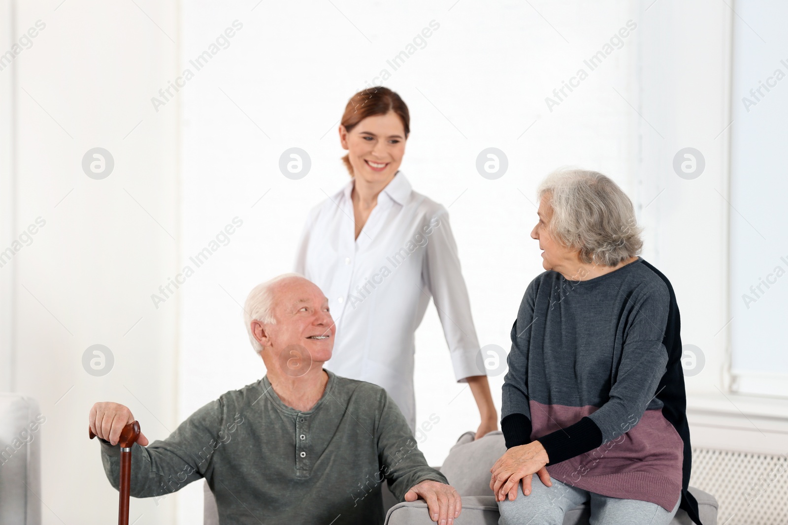 Photo of Elderly spouses with female caregiver in living room