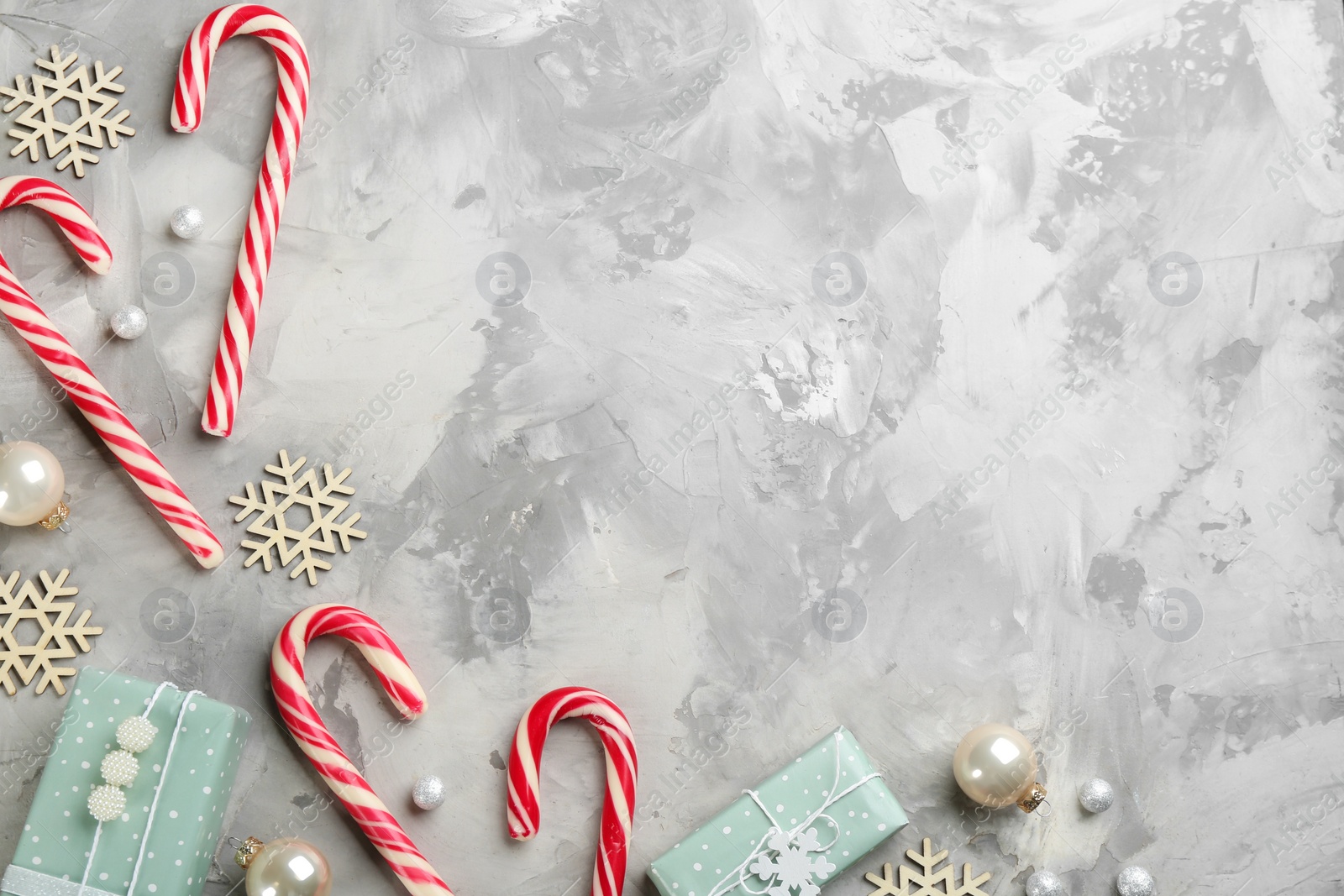 Photo of Flat lay composition with candy canes and Christmas decor on grey table. Space for text