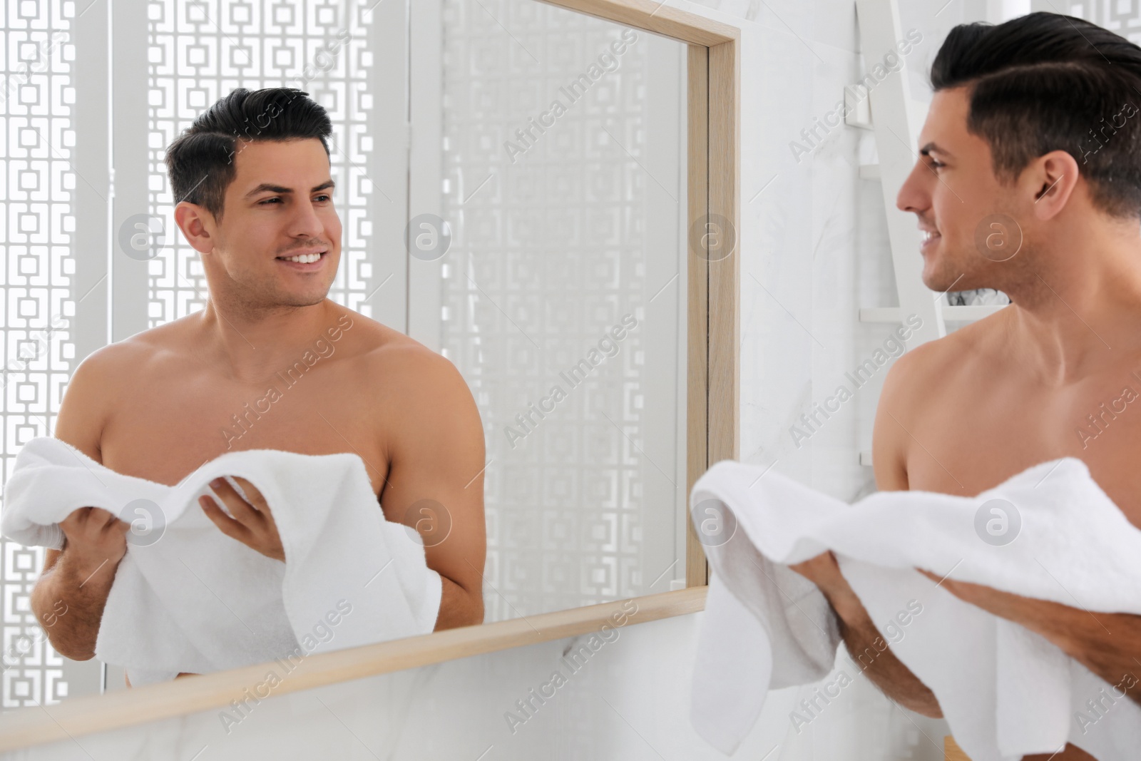 Photo of Handsome man with towel near mirror in bathroom after shaving