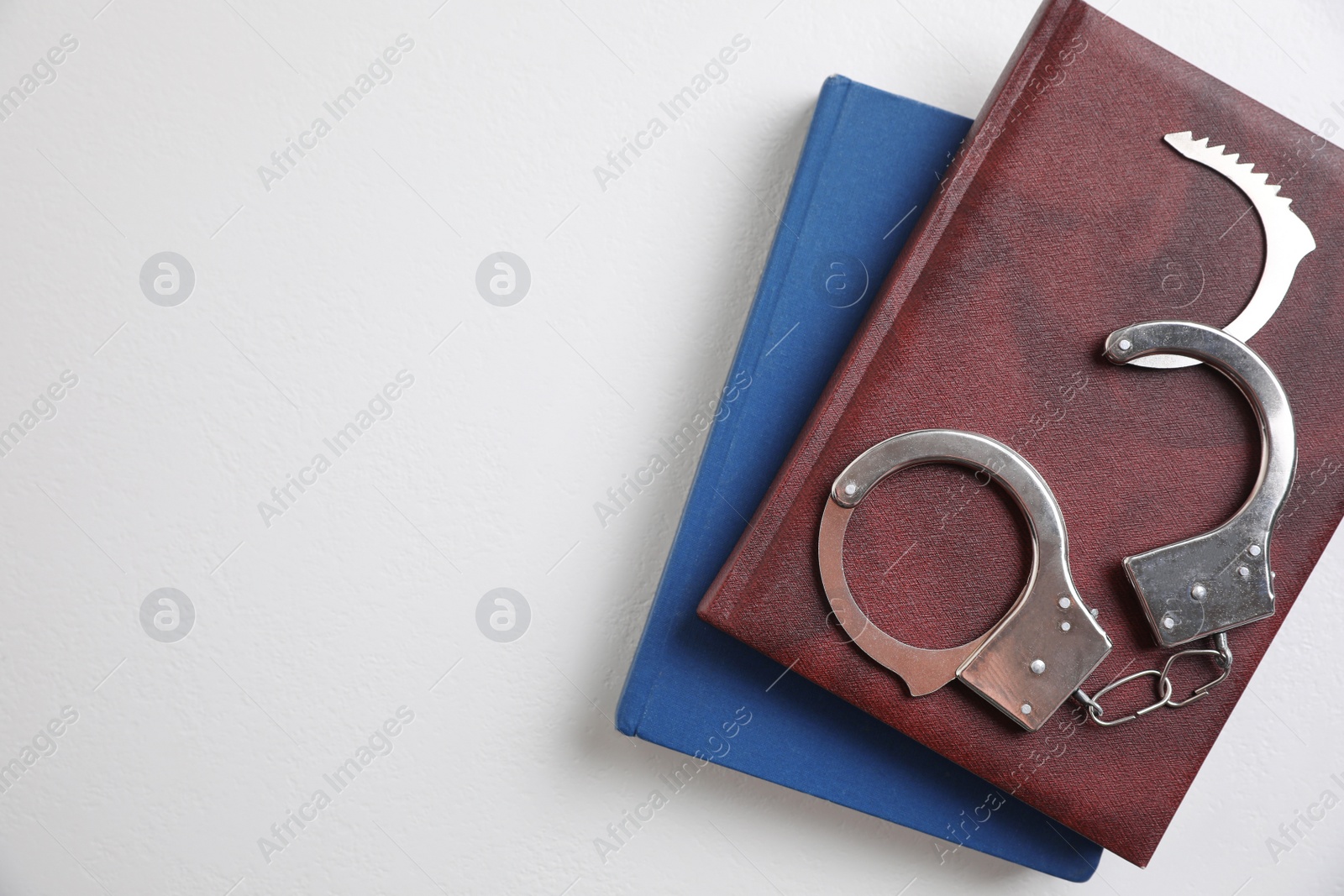 Photo of Flat lay composition with books and handcuffs on white background, space for text. Criminal law