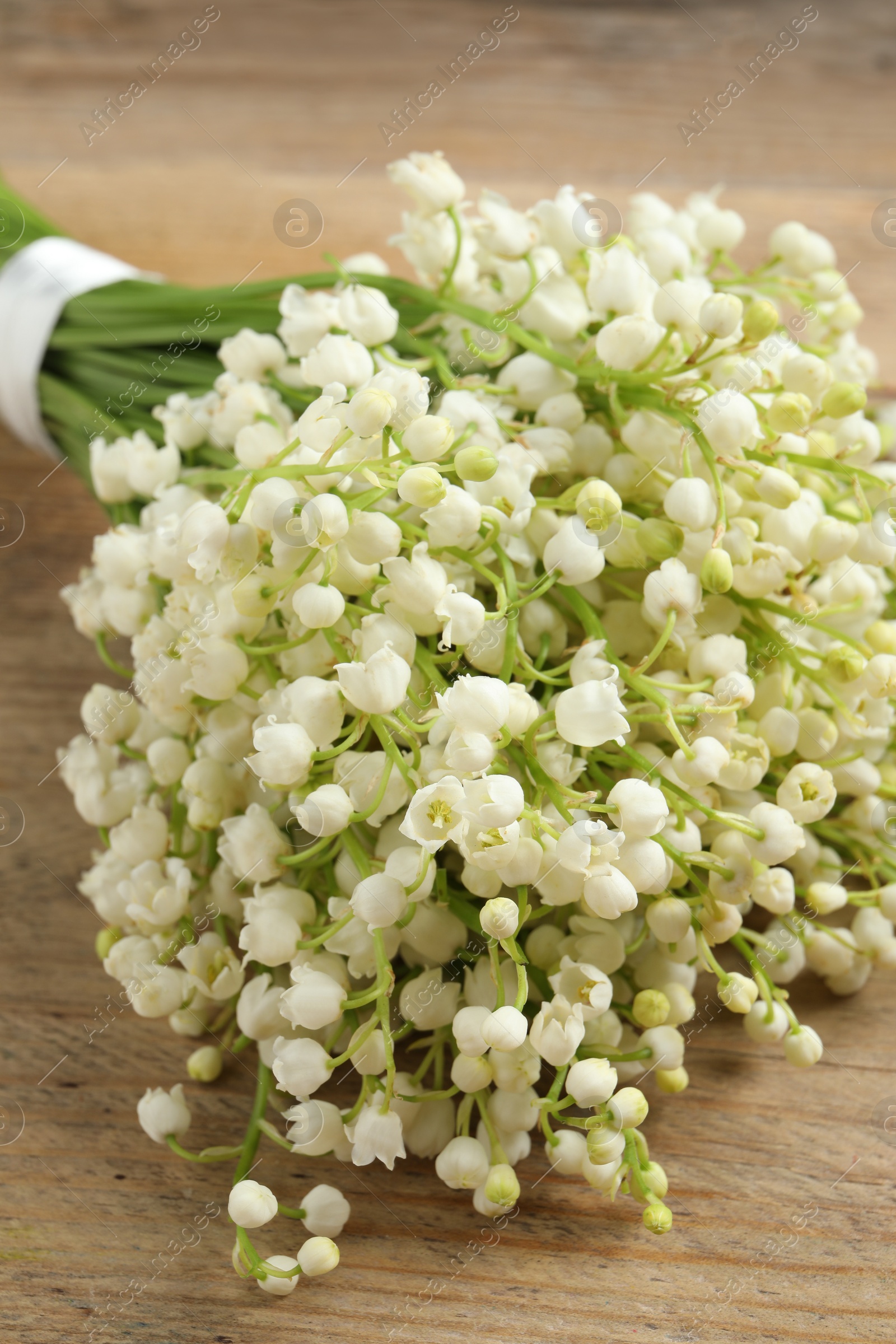 Photo of Beautiful lily of the valley bouquet on wooden table, closeup