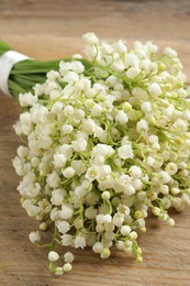 Photo of Beautiful lily of the valley bouquet on wooden table, closeup