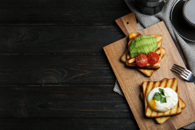 Photo of Delicious poached egg with toasted bread and garnish served on black wooden table, flat lay. Space for text