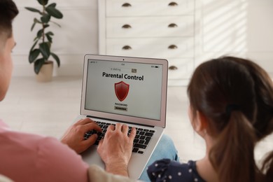 Father installing parental control app on laptop to ensure his child's safety at home