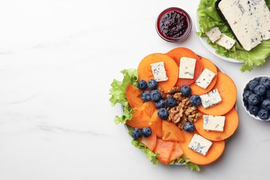 Delicious persimmon with blue cheese on white marble table, flat lay. Space for text